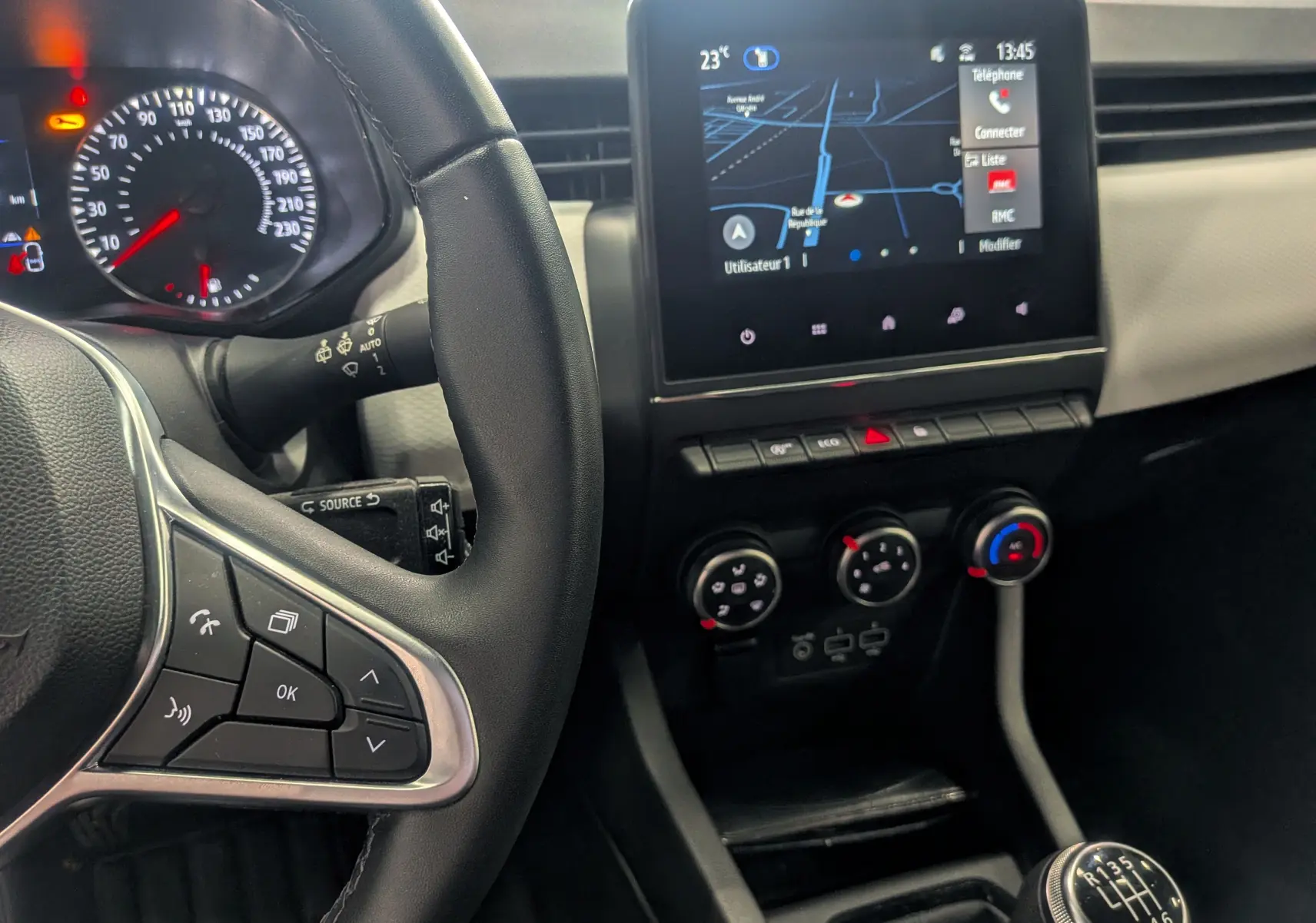 Vue intérieure de la Renault Clio V TCe 100 GPL, tableau de bord avec écran tactile et levier de vitesses manuel.