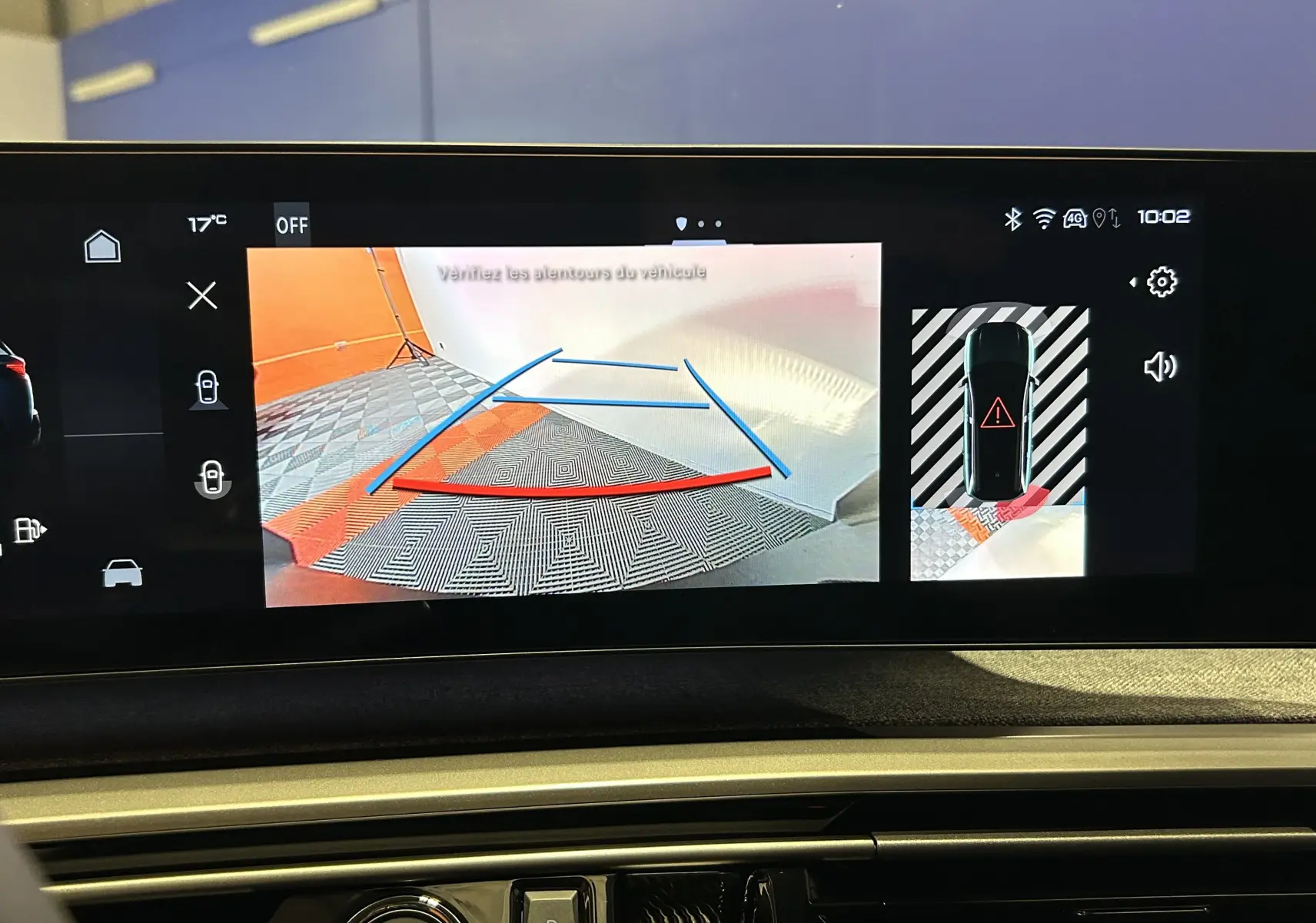 Écran multimédia montrant la caméra de recul et l'alerte de proximité du Peugeot 5008 gris titane en stationnement.