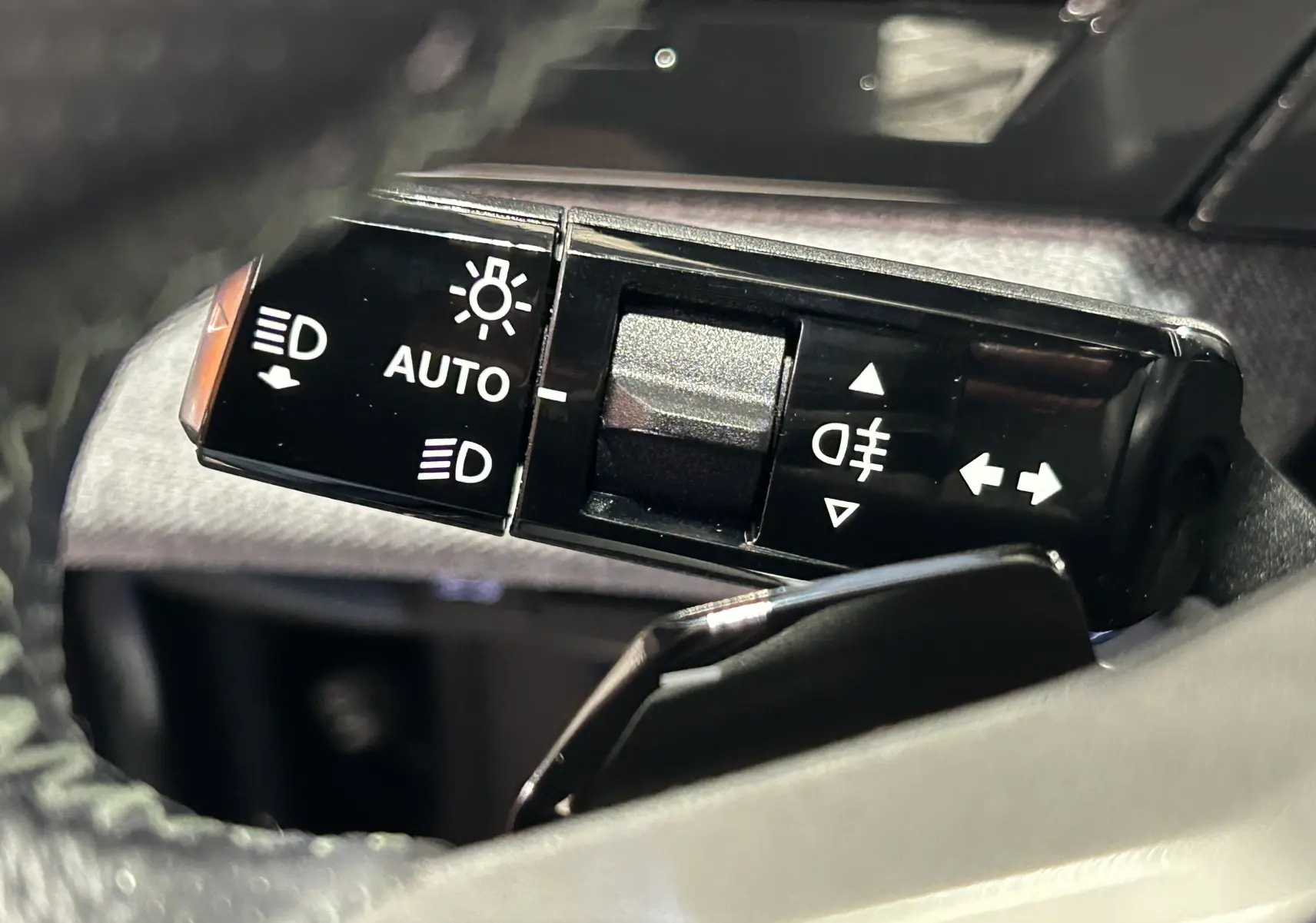 Gros plan sur la commande des phares et clignotants du Peugeot 5008 Hybrid gris titane, intérieur noir.