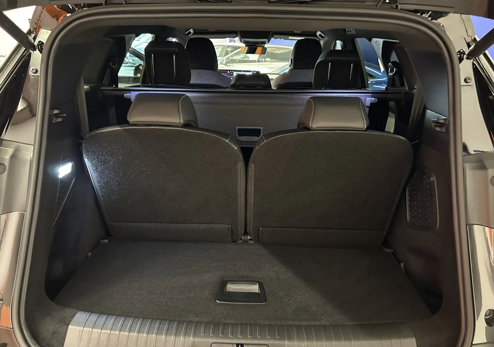 Vue arrière du coffre ouvert du Peugeot 5008 gris titane, montrant les sièges arrière rabattus et l'intérieur spacieux.