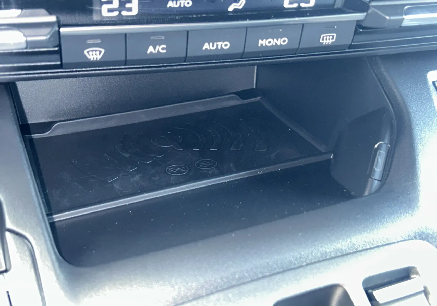 Gros plan sur la console centrale du Citroën Berlingo Multispace 2026, zone de recharge sans fil et commandes de climatisation.