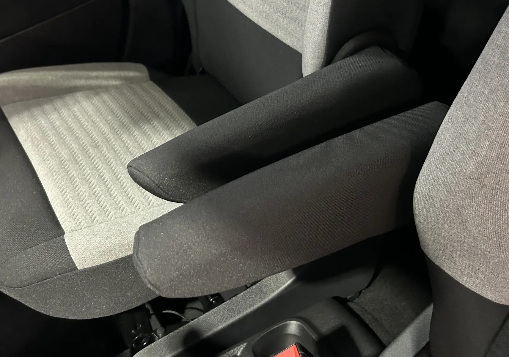 Détail des sièges avant tissu gris et noir avec accoudoirs relevés dans l’habitacle du Citroën Berlingo Multispace.