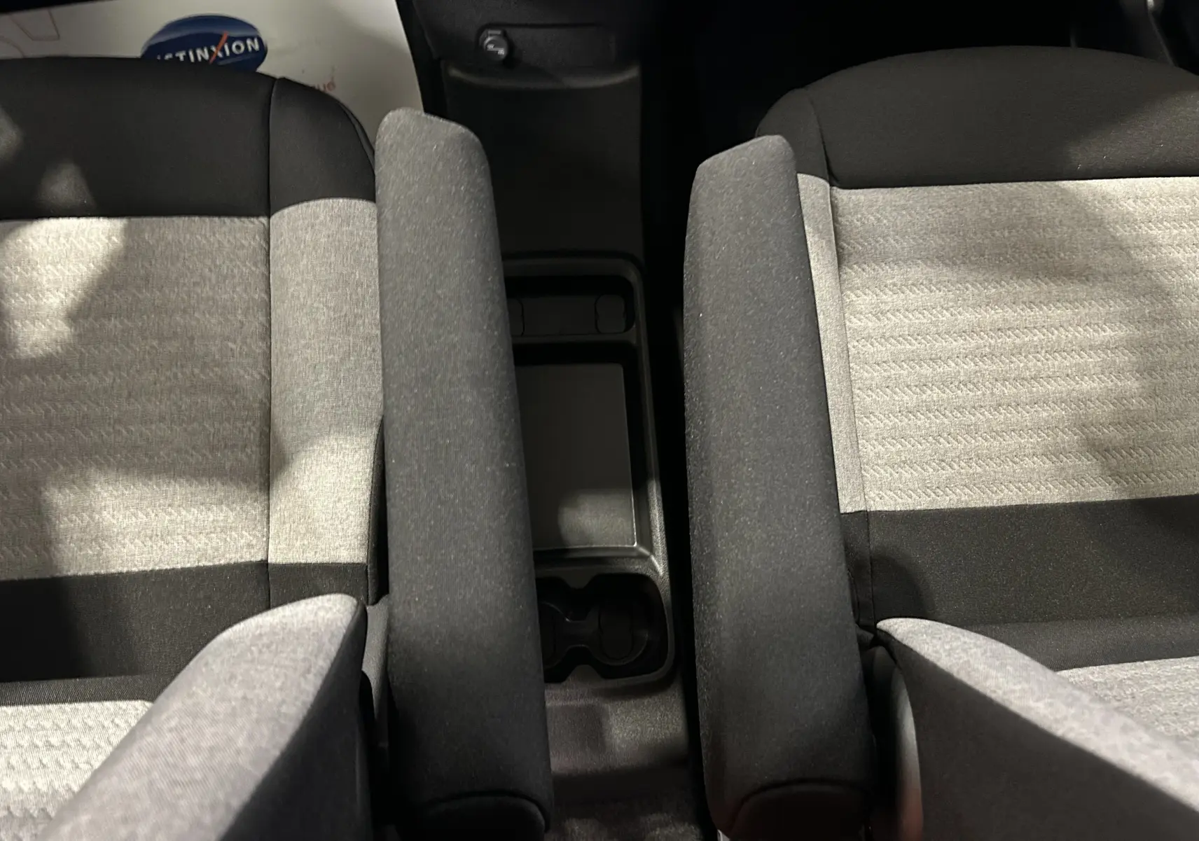 Vue rapprochée des sièges avant gris et noirs du Citroën Berlingo Multispace avec accoudoirs centraux relevés.