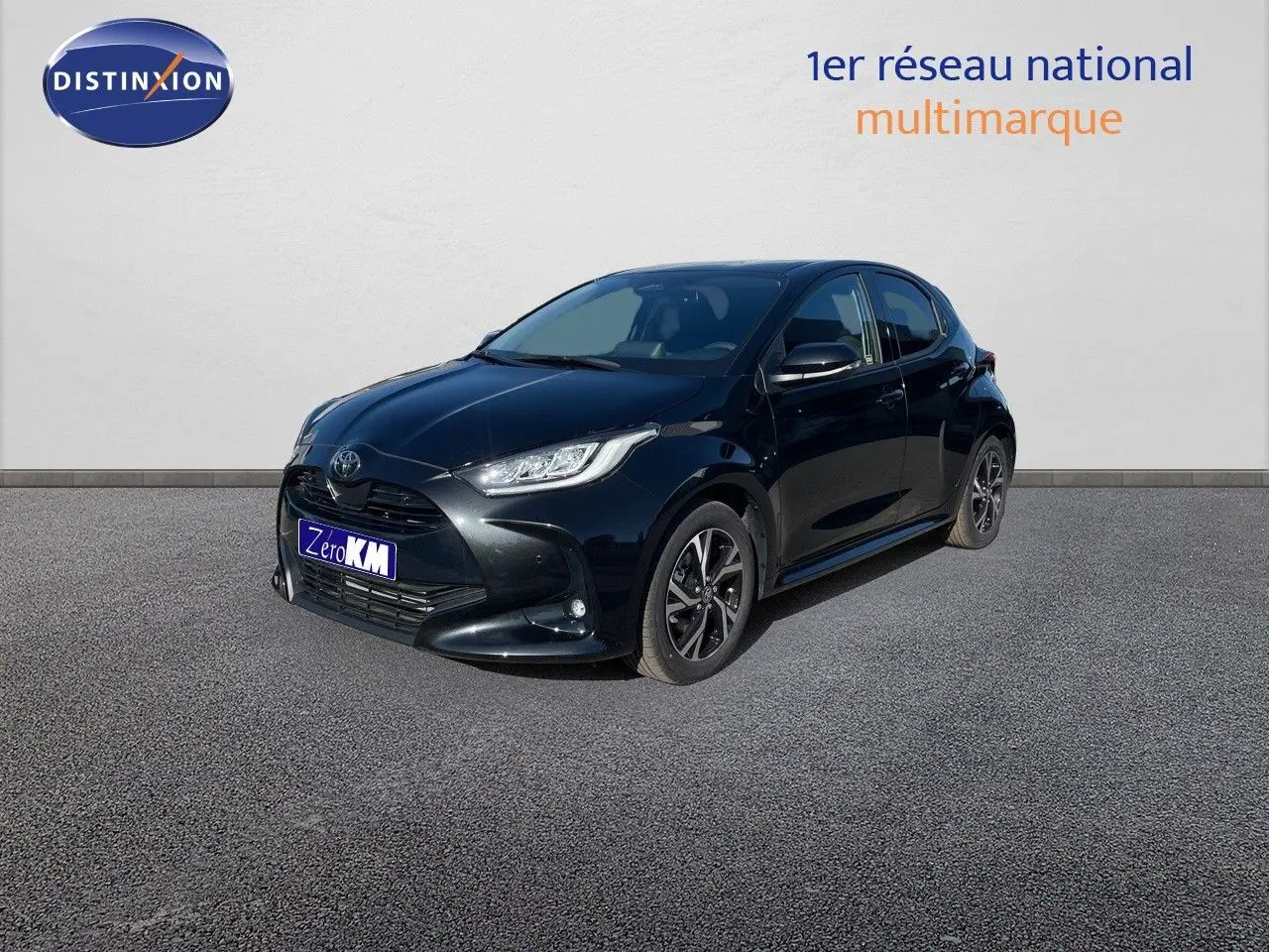 Toyota Yaris Hybrid noir métal vue 3/4 avant droit avec jantes bi-ton et feux LED allumés.