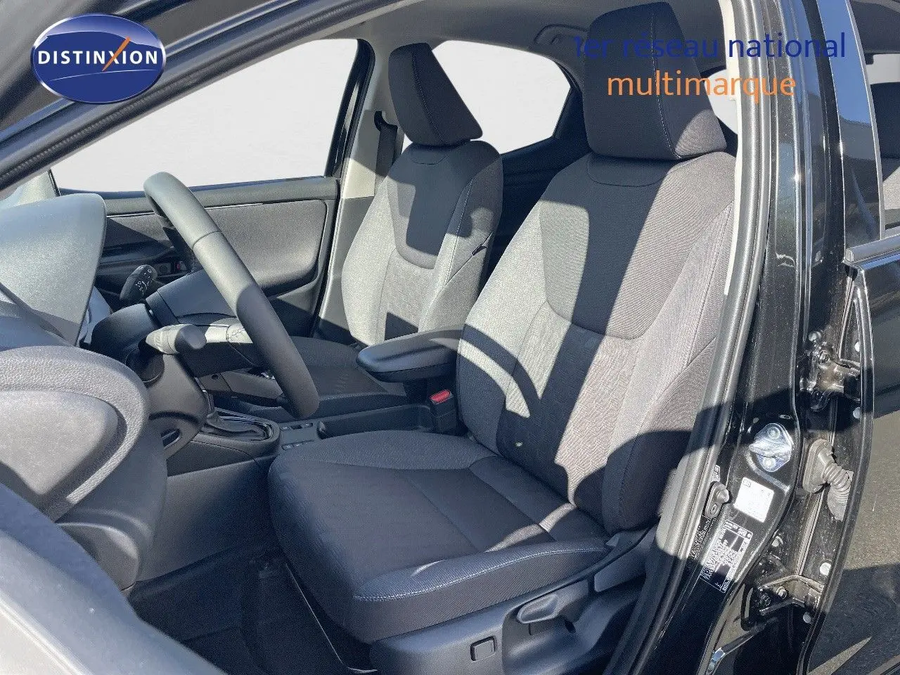 Vue intérieure côté conducteur de la Toyota Yaris Hybrid 116ch 2025 avec sièges tissu noir gris et volant noir.