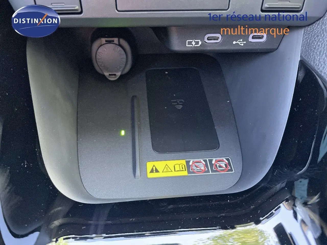 Gros plan sur la console centrale de la Toyota Yaris Hybrid 2025 noire, montrant le chargeur sans fil et ports USB.