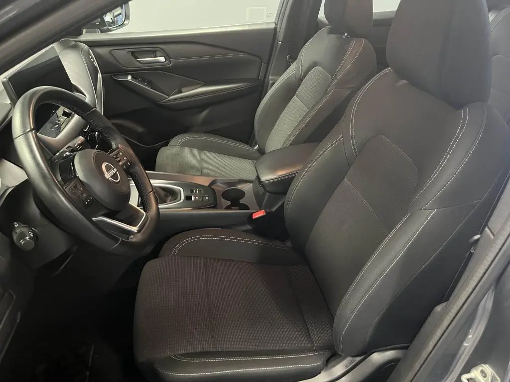 Intérieur côté conducteur du Nissan Qashqai 1.3 Mild Hybrid 2023 avec sièges tissu noir et volant cuir.
