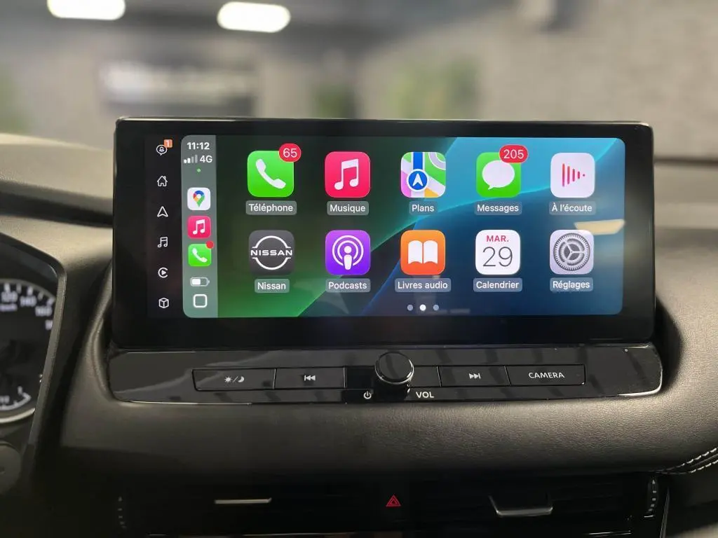 Écran tactile 9 pouces du Nissan Qashqai 2023 affichant Apple CarPlay sans fil et commandes sous l'écran.