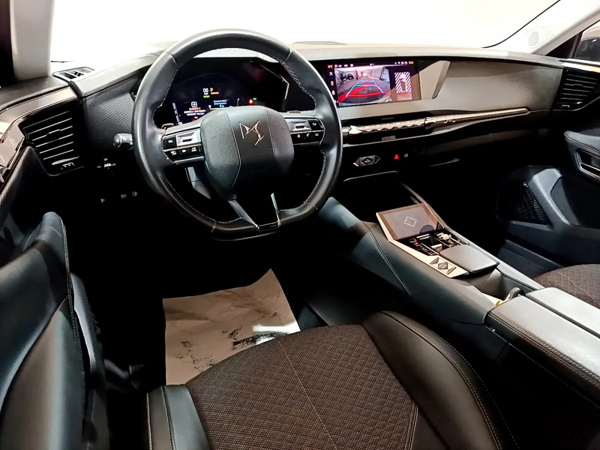 Intérieur du DS4 E-TENSE 2023 vu côté conducteur, volant cuir, tableau de bord numérique et écran tactile central.