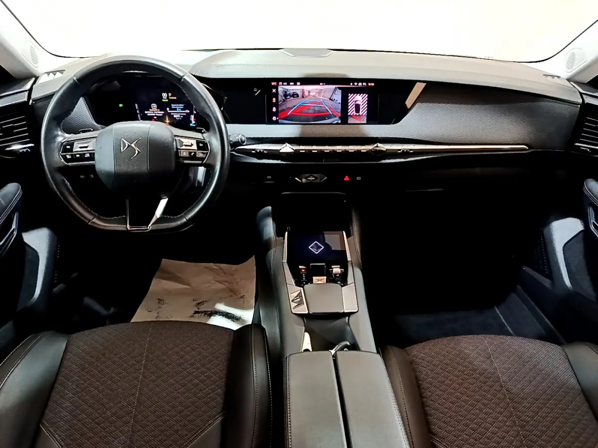 Intérieur noir du DS4 E-TENSE 2023 vu de face, avec volant cuir et écran tactile central affichant la caméra de recul
