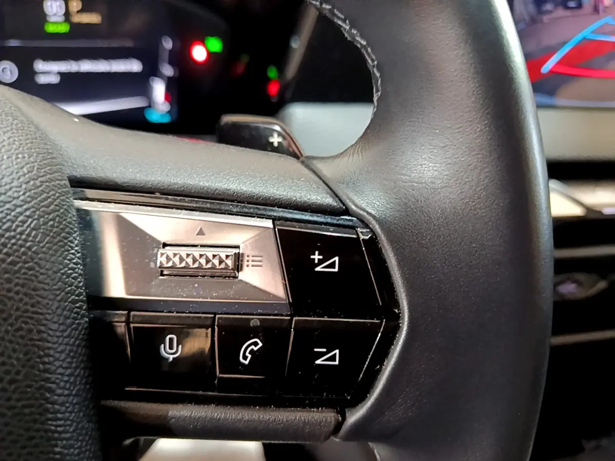 Gros plan sur les commandes du volant cuir noir du DS4 E-TENSE 225 TROCADERO, boutons multifonctions visibles.