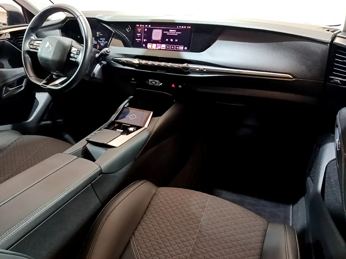 Intérieur noir de la DS4 E-TENSE 2023 vu côté passager, avec tableau de bord digital et volant cuir multifonctions.