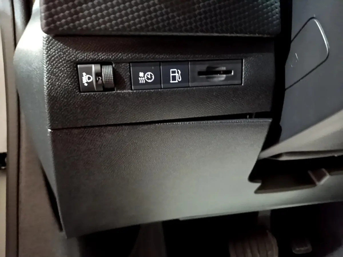 Vue rapprochée des commandes de réglage des phares et du tableau de bord côté gauche intérieur du DS4 E-TENSE gris foncé 2023.