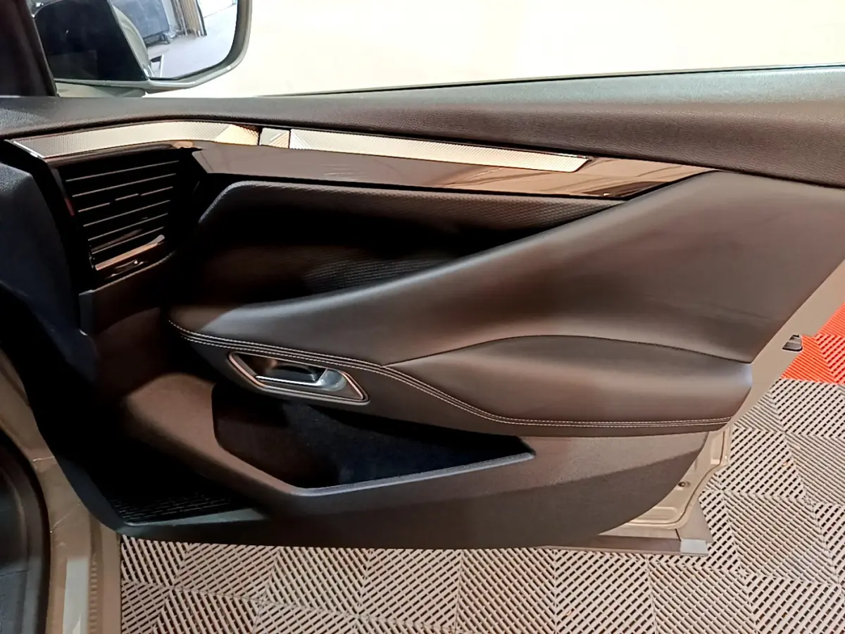 Gros plan sur la porte côté gauche du DS4 E-TENSE 225 TROCADERO gris foncé, avec garniture cuir et insert brillant.