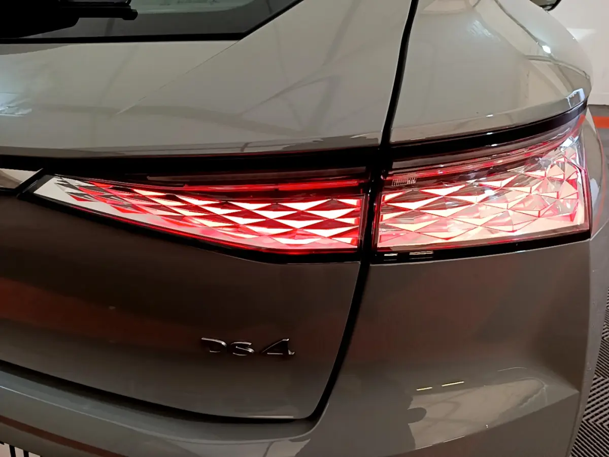 Gros plan sur le feu arrière droit rouge et blanc du DS4 gris foncé, avec le logo DS4 visible sur le coffre.