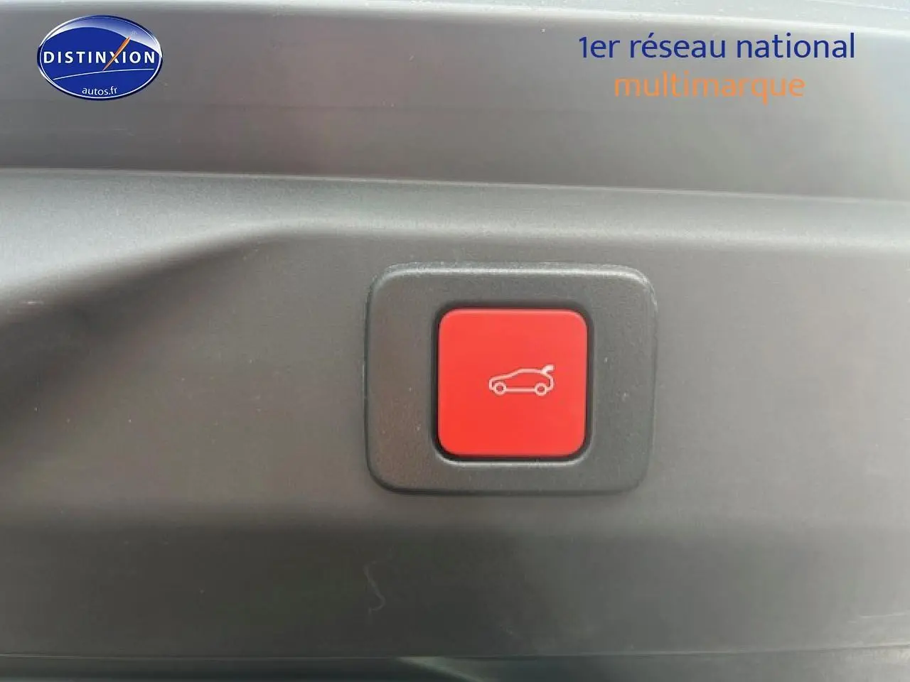 Bouton rouge d'ouverture électrique du coffre sur un Peugeot 3008 gris Artense, vue rapprochée intérieure.
