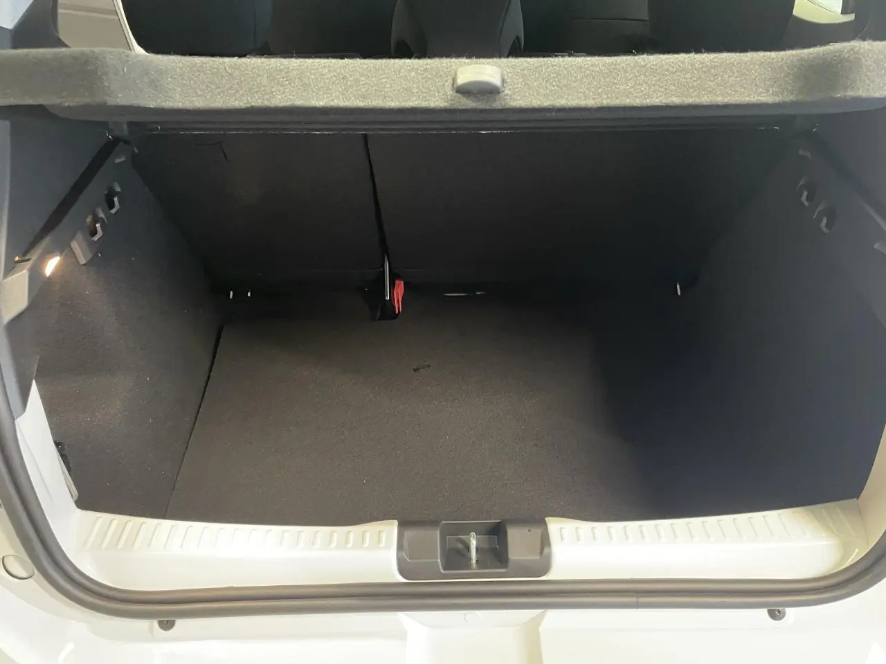 Coffre ouvert vu de l'arrière d'une Dacia Sandero Stepway blanc glacier 2025 avec plancher plat et roue de secours.