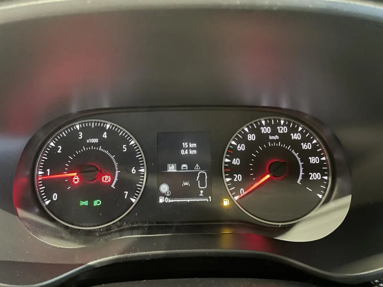 Tableau de bord du Dacia Sandero 2025 avec compte-tours, compteur de vitesse et écran central affichant 15 km et alertes.