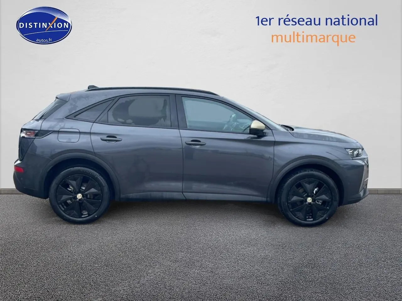 Vue latérale droite d'un DS7 gris titane avec jantes noires et vitres arrière surteintées sur fond neutre.