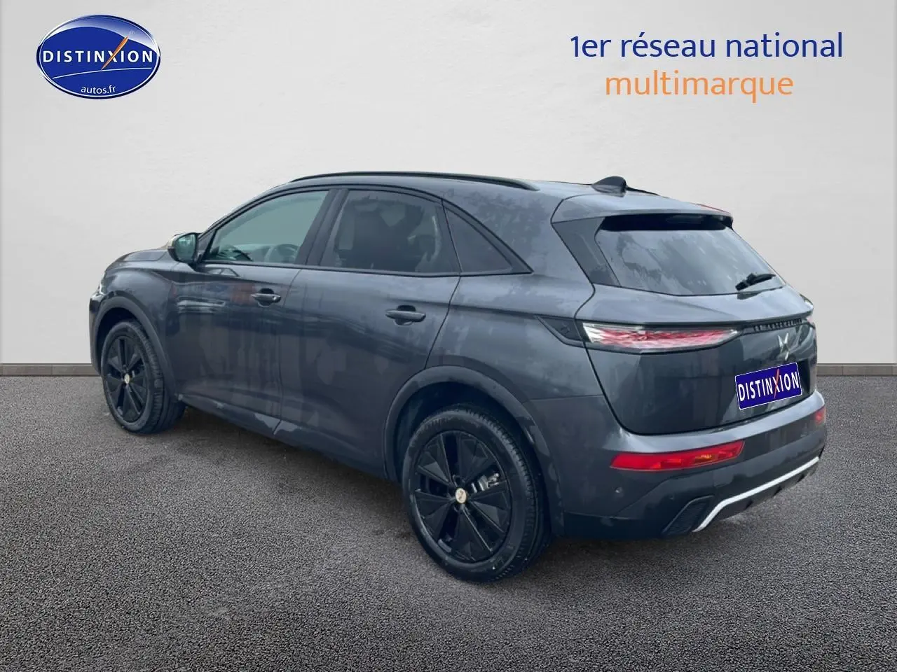 Vue 3/4 arrière droite d'un DS7 gris titane avec jantes noires et feux arrière LED allumés.