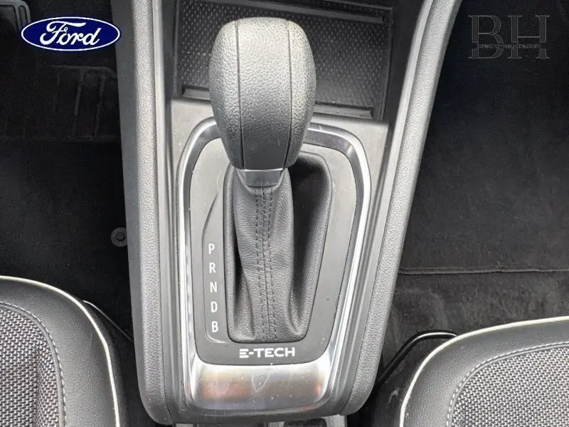 Le levier de vitesses automatique noir marqué E-TECH, vu de dessus, entre deux sièges gris foncé.