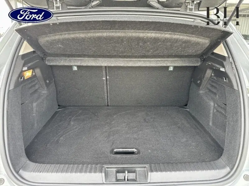 Coffre ouvert vu de l'arrière d'un Renault Captur gris Highland, espace de chargement propre et vide.