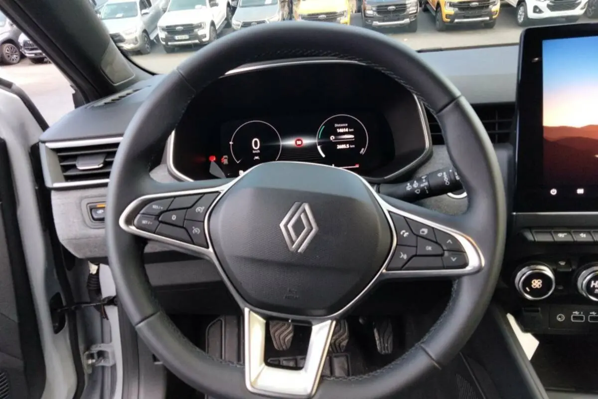 Vue intérieure centrée sur le volant cuir multifonctions de la Renault Clio 2025 avec tableau de bord numérique et écran tactile.