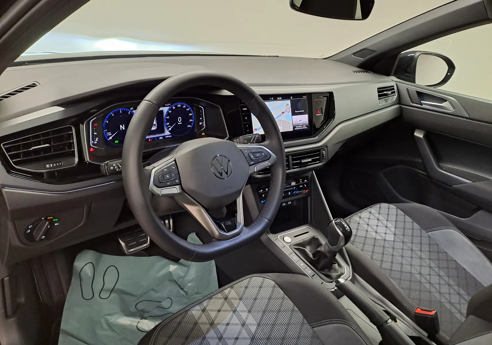 Vue intérieure côté conducteur du Volkswagen Taigo 2025, tableau de bord numérique et sièges tissu à motifs gris.