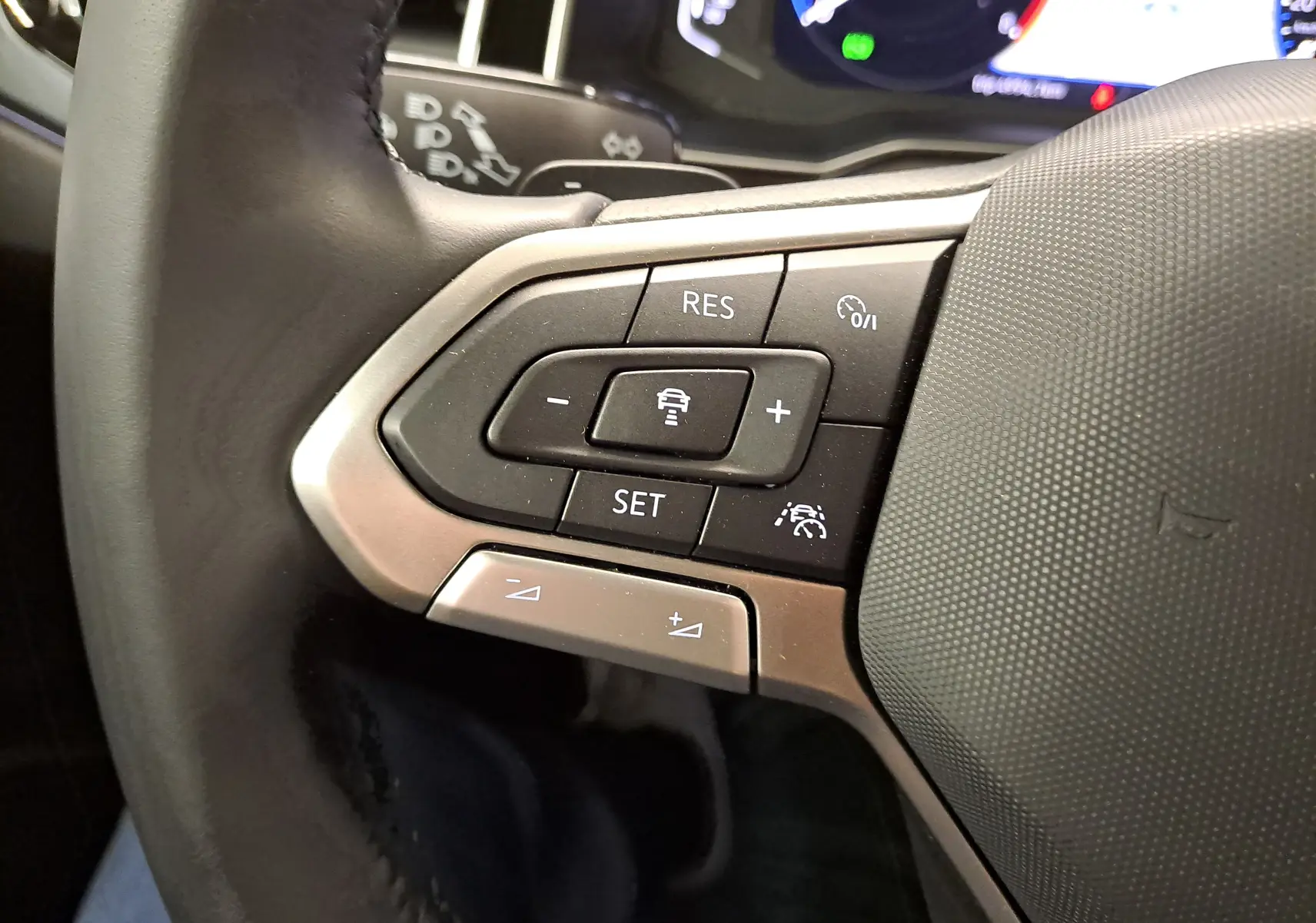 Gros plan sur les commandes multifonctions du volant côté gauche du Volkswagen Taigo noir intense nacré, version R-Line 2025.