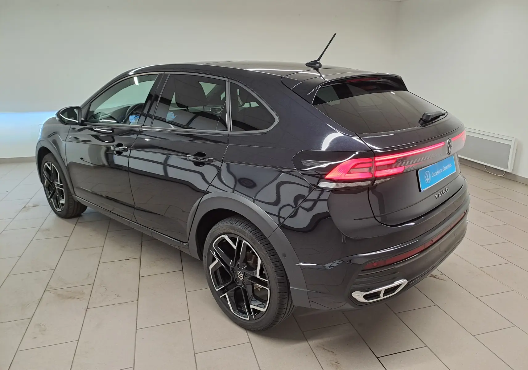 Vue 3/4 arrière droite du Volkswagen Taigo noir intense nacré avec feux arrière LED et jantes alliage noires.