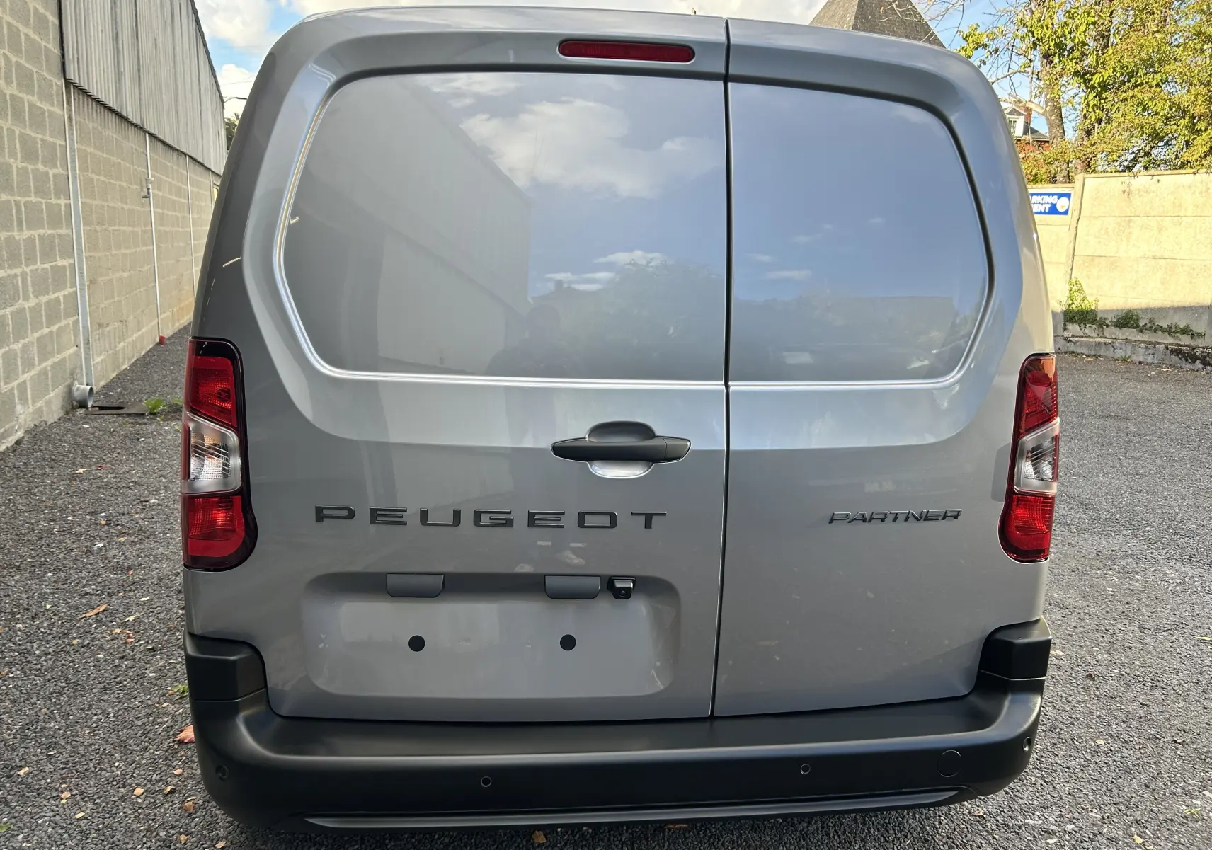 Vue arrière du Peugeot Partner Fourgon gris acier, avec portes battantes et feux arrière rouges.