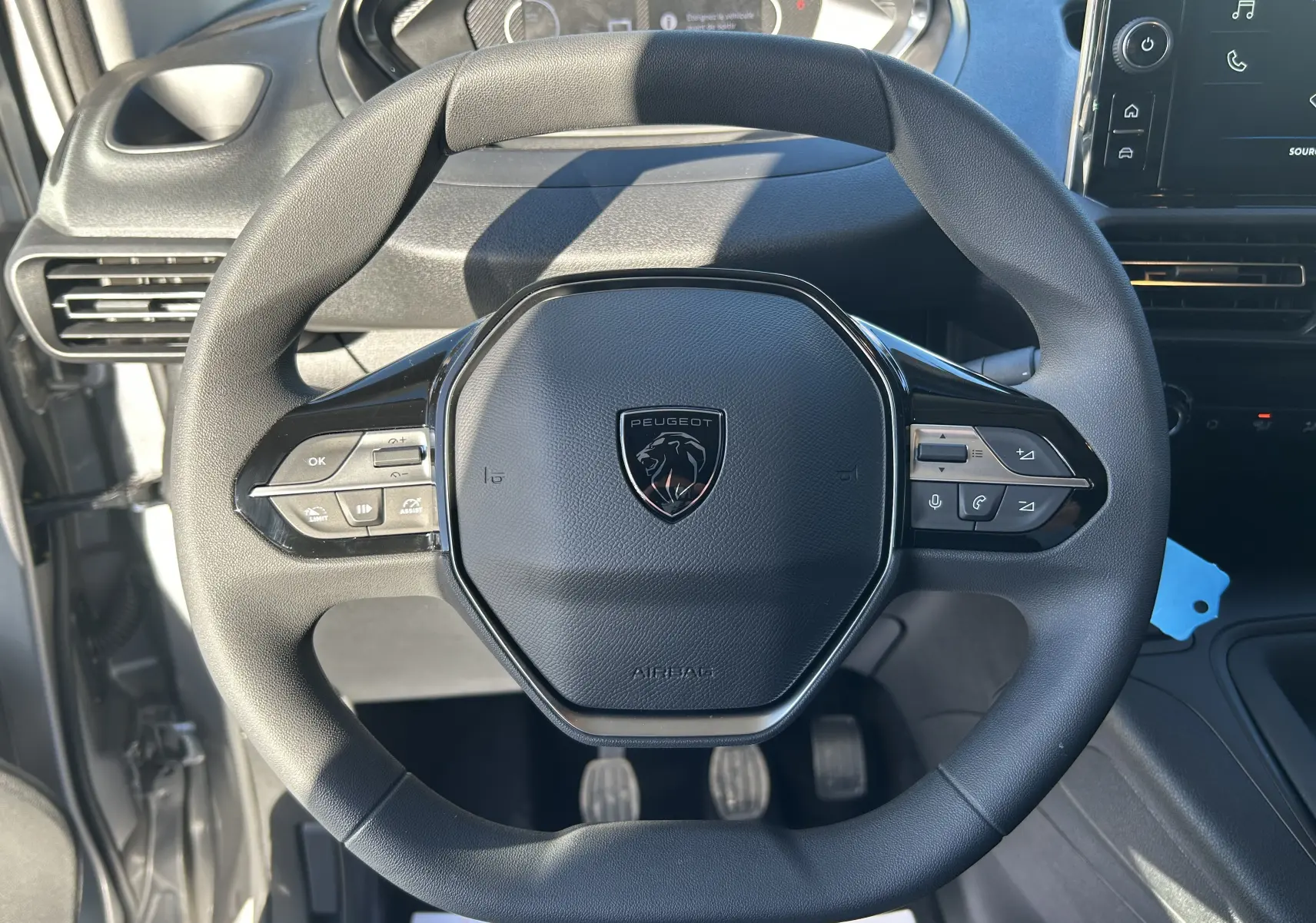 Vue rapprochée du volant multifonction noir du Peugeot Partner Fourgon 2026 avec tableau de bord et commandes visibles.