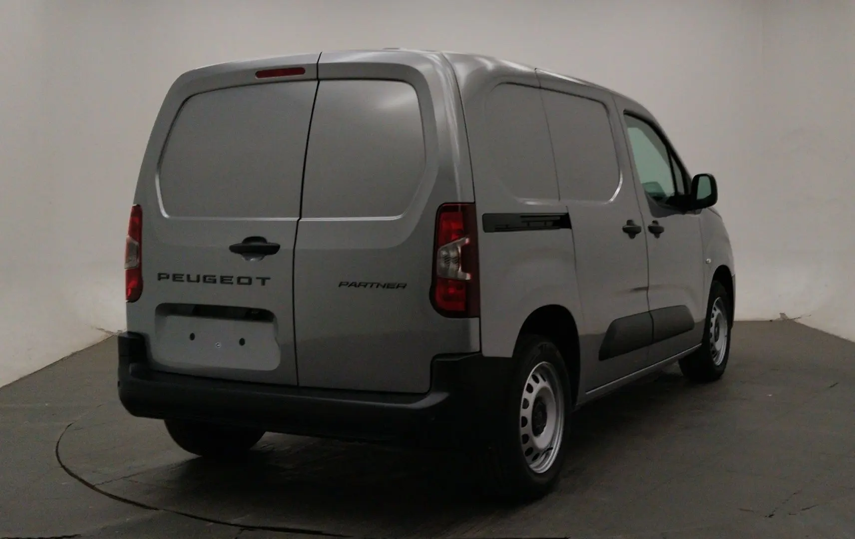 Vue 3/4 arrière droit du Peugeot Partner Fourgon gris acier avec portes arrière battantes et jantes acier.