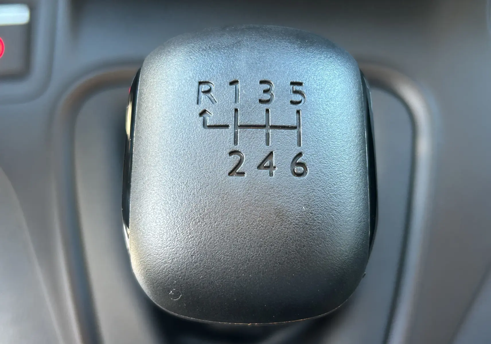 Gros plan sur le pommeau de la boîte manuelle 6 vitesses du Peugeot Partner Fourgon gris acier, intérieur sombre.