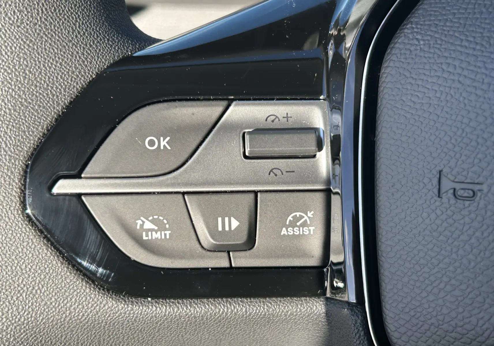 Gros plan sur les commandes de régulateur et limiteur de vitesse à gauche du volant du Peugeot Partner Fourgon gris acier.