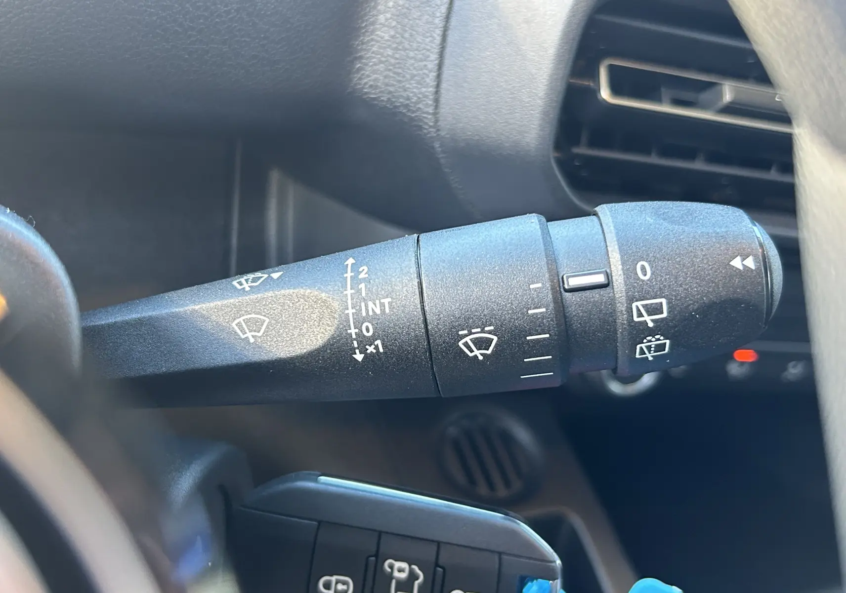 Gros plan sur la commande d’essuie-glace côté gauche du tableau de bord du Peugeot Partner Fourgon gris acier 2026.