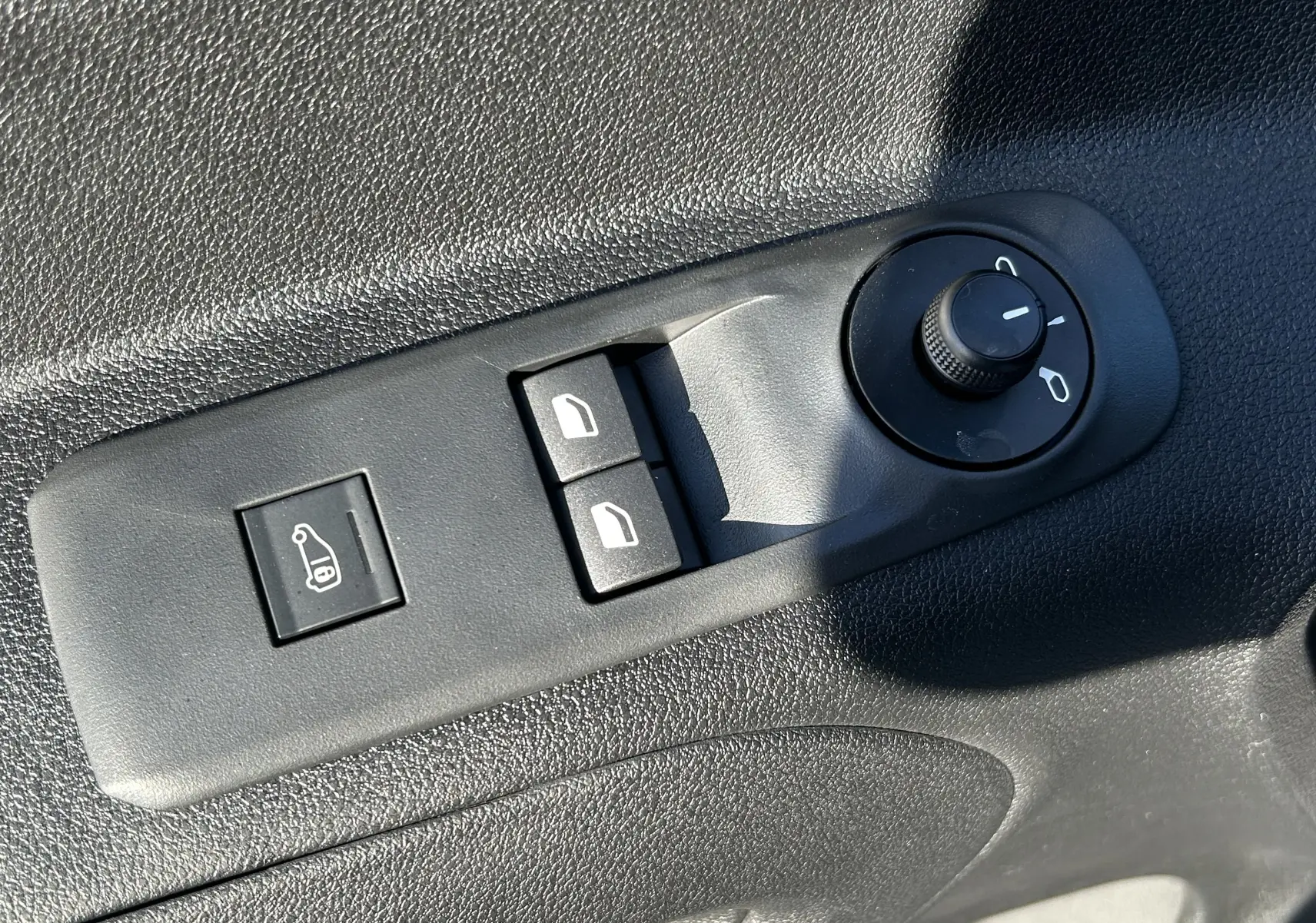 Gros plan sur les commandes de réglage des rétroviseurs et des vitres électriques côté conducteur du Peugeot Partner Fourgon gris acier.