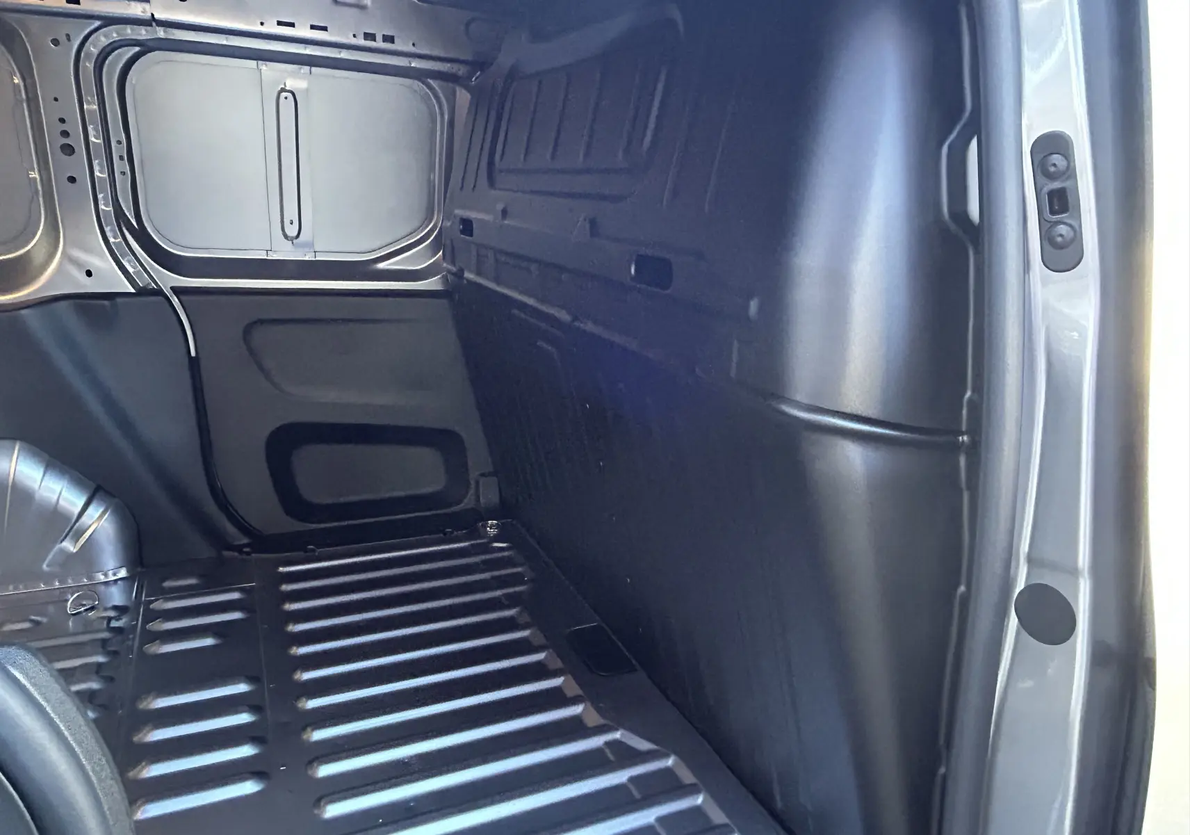 Intérieur du coffre côté droit du Peugeot Partner Fourgon gris acier, montrant la paroi et le plancher métallique.