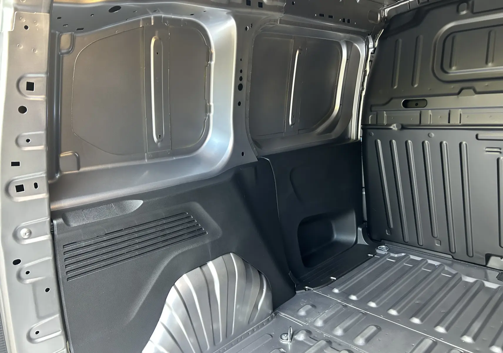 Intérieur du fourgon Peugeot Partner gris acier, vue sur la paroi et le plancher métallique côté gauche du coffre.