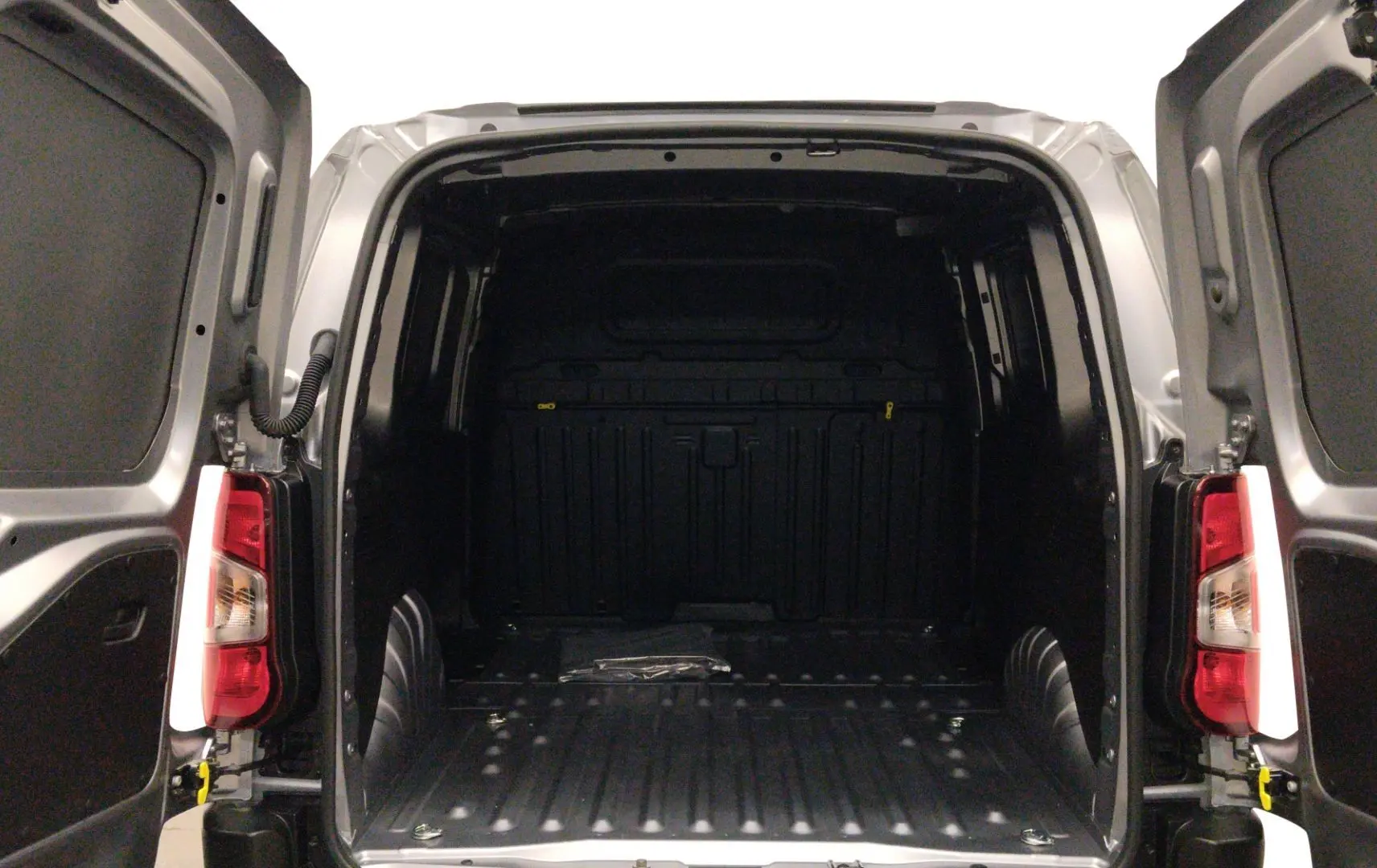 Vue arrière ouverte du Peugeot Partner Fourgon gris acier, montrant l'espace de chargement vide et les portes battantes ouvertes.