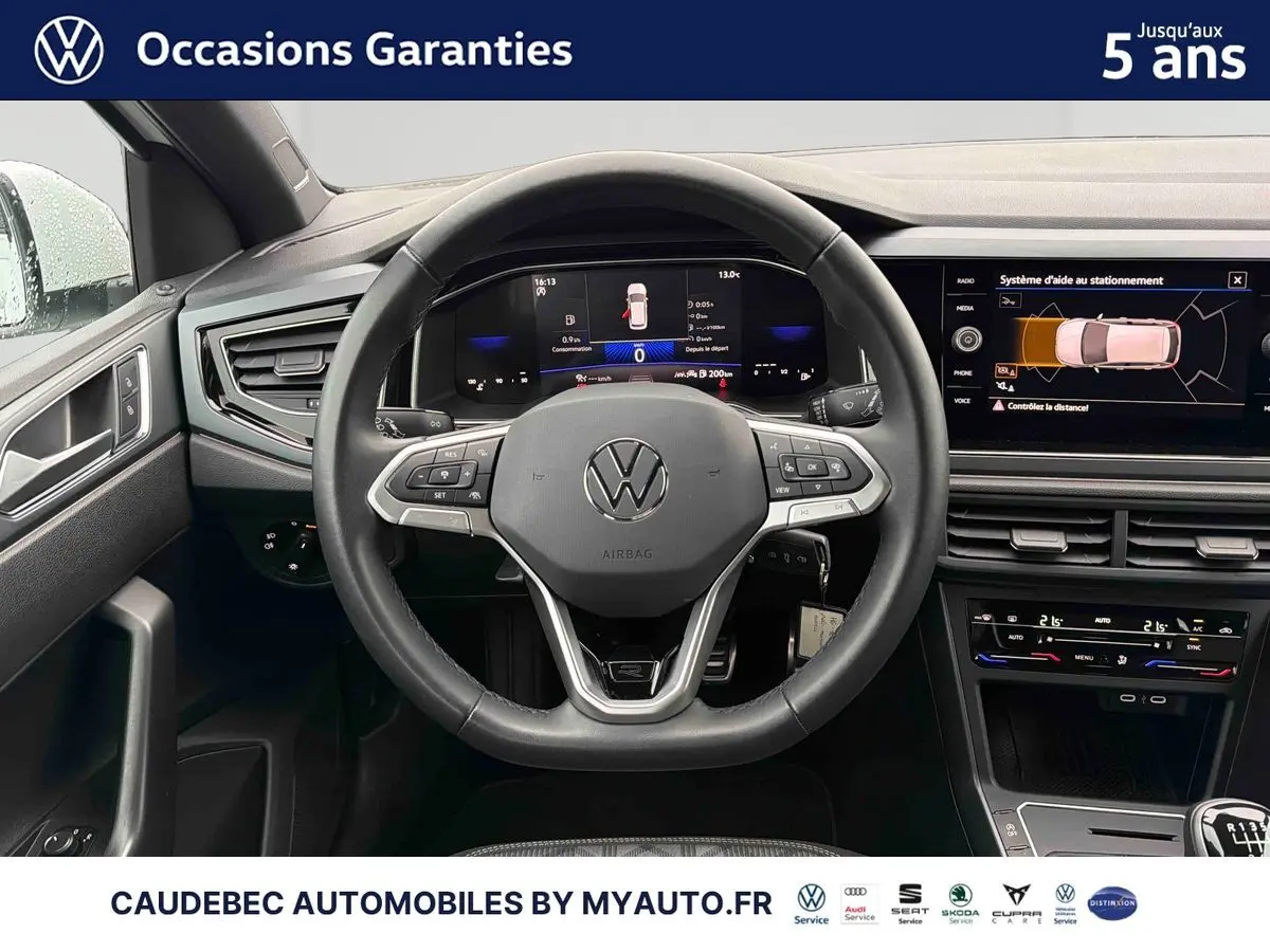 Vue intérieure centrée sur le volant cuir multifonctions et le tableau de bord digital d'une Volkswagen Polo blanche 2025.