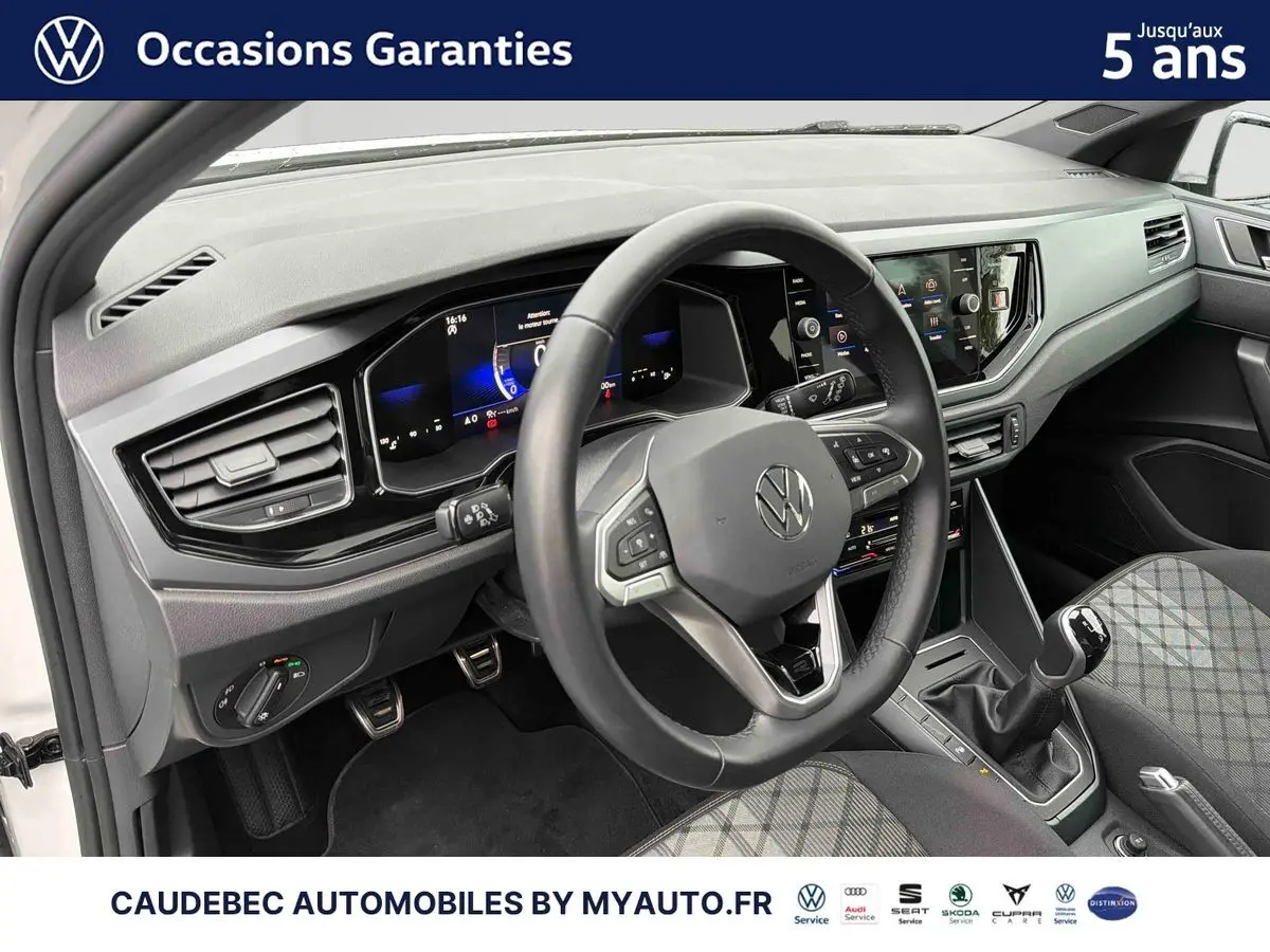 Vue intérieure côté conducteur de la Volkswagen Polo blanche 2025, volant cuir et tableau de bord digital.