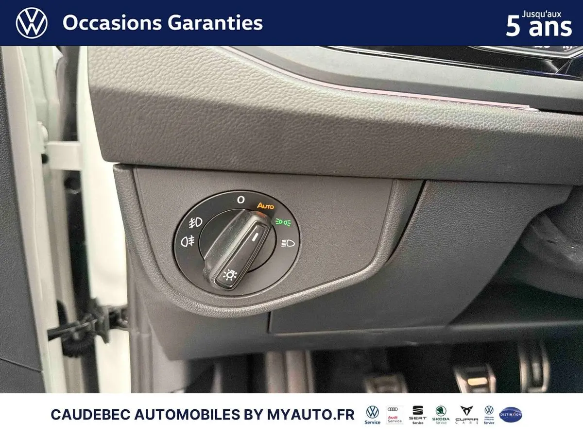 Détail du bouton de commande des feux sur le tableau de bord côté gauche d'une Volkswagen Polo blanche.