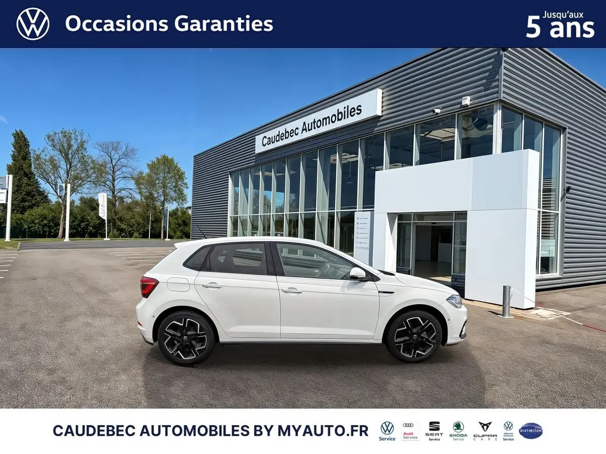 Profil droit d'une Volkswagen Polo blanche 2025 avec jantes alliage 17 pouces, devant un bâtiment Caudebec Automobiles.