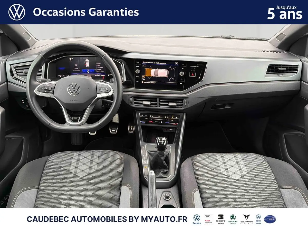 Vue intérieure avant de la Volkswagen Polo blanche 2025, volant cuir, boîte manuelle et écran tactile central.