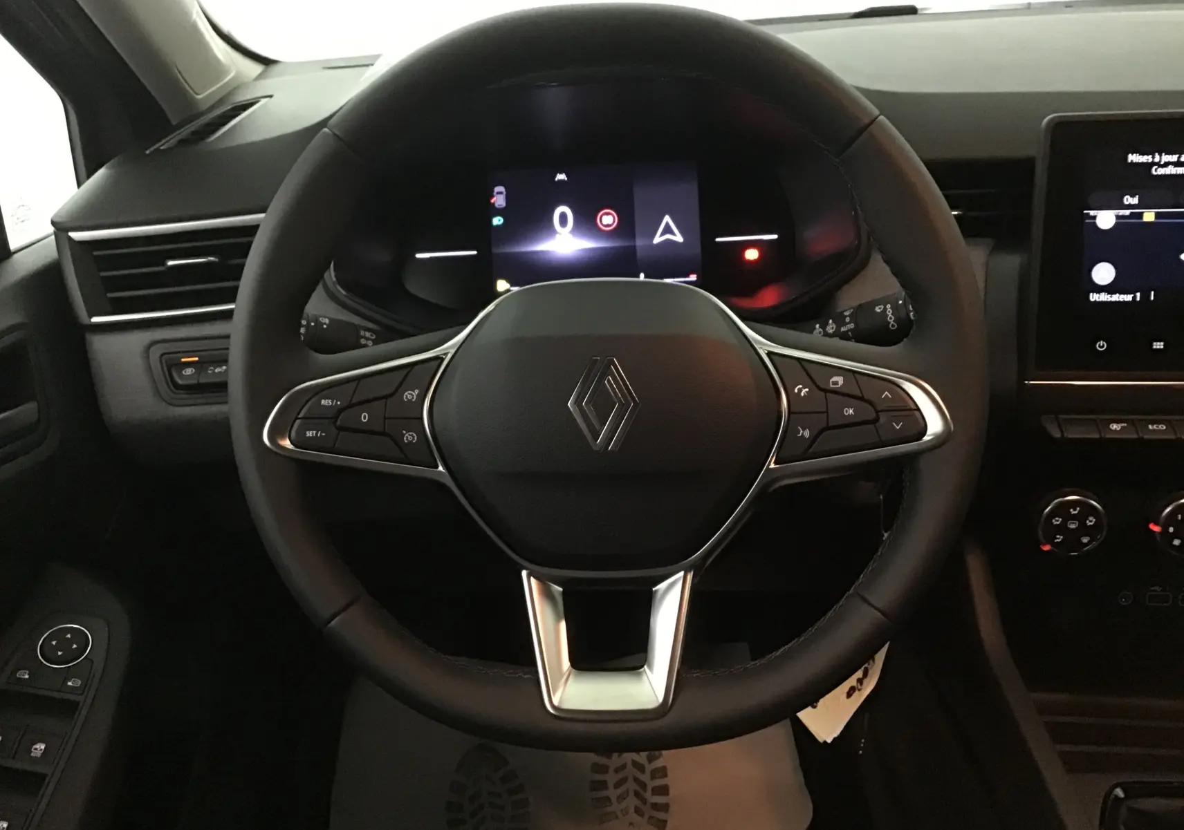 Vue frontale du volant noir de la Renault Clio V 2025 avec tableau de bord numérique et commandes intégrées.