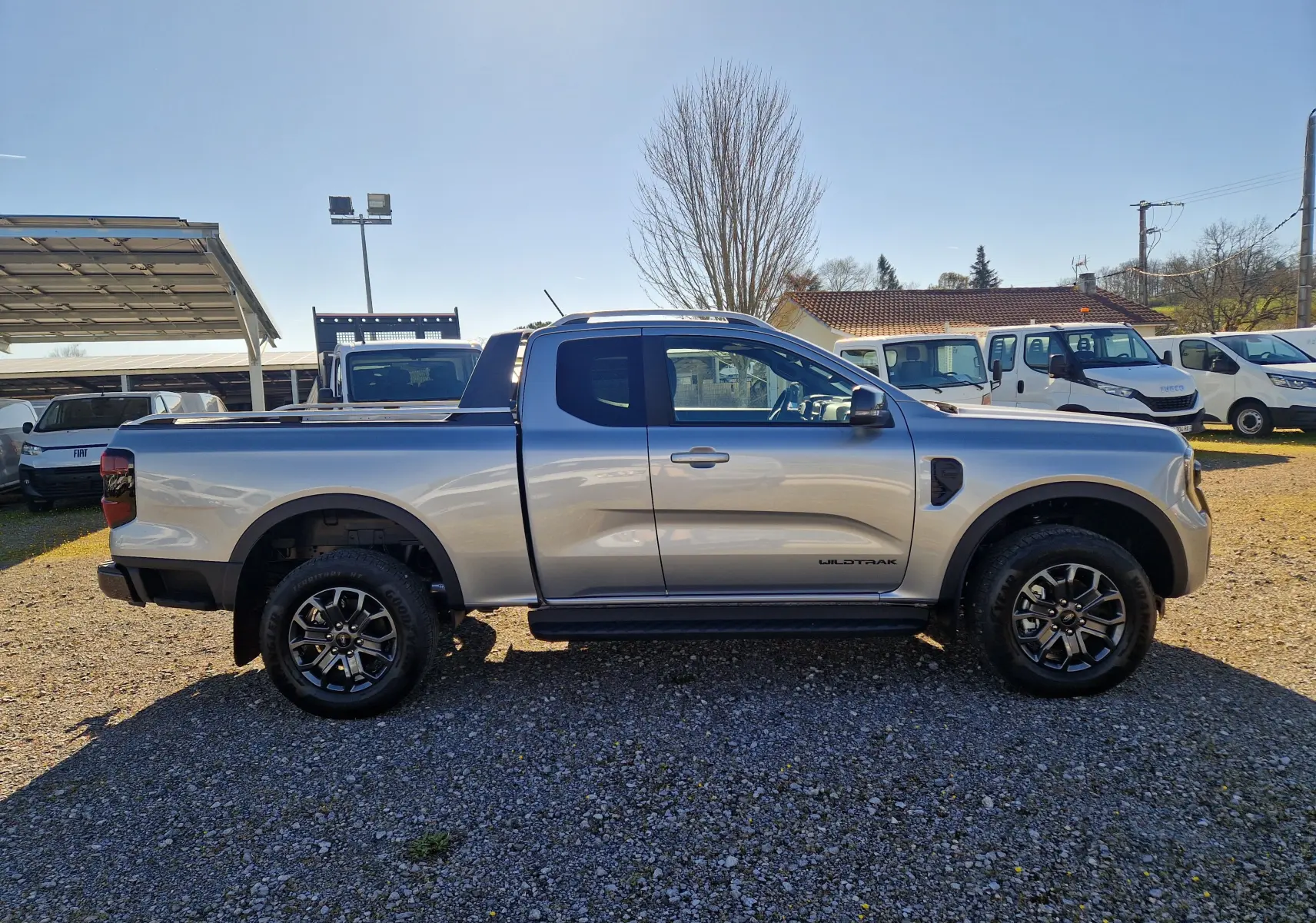 Vue de profil côté gauche du Ford Ranger Super Cabine Wildtrak gris iconic avec jantes alliage et marquage Wildtrak sur la porte.