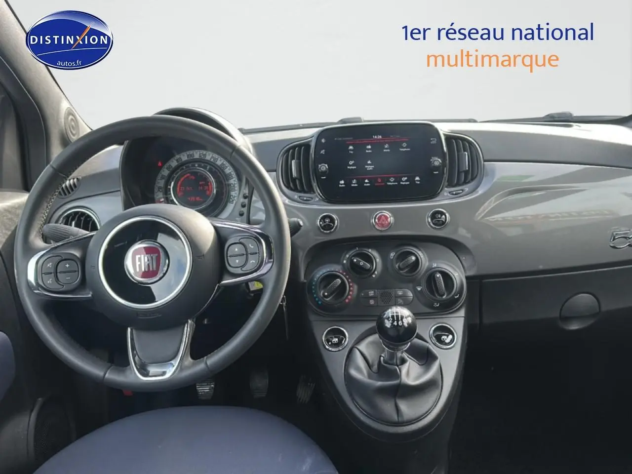 Vue intérieure du tableau de bord gris de la Fiat 500 1.0 70 bsg cult avec volant cuir et boîte manuelle.