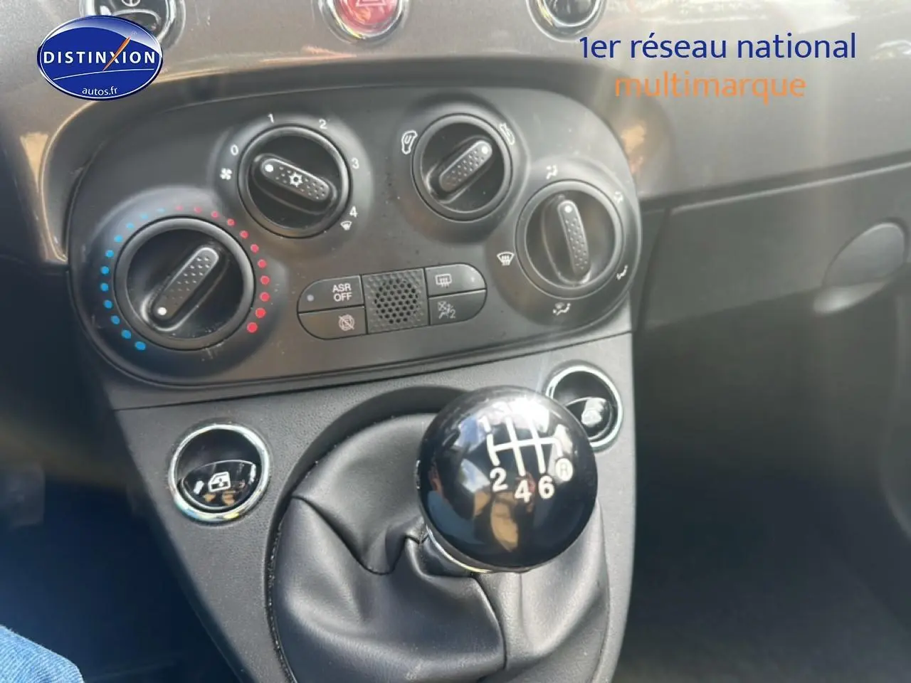 Le levier de vitesses manuel noir et la console centrale avec commandes de climatisation d'une Fiat 500 grise.