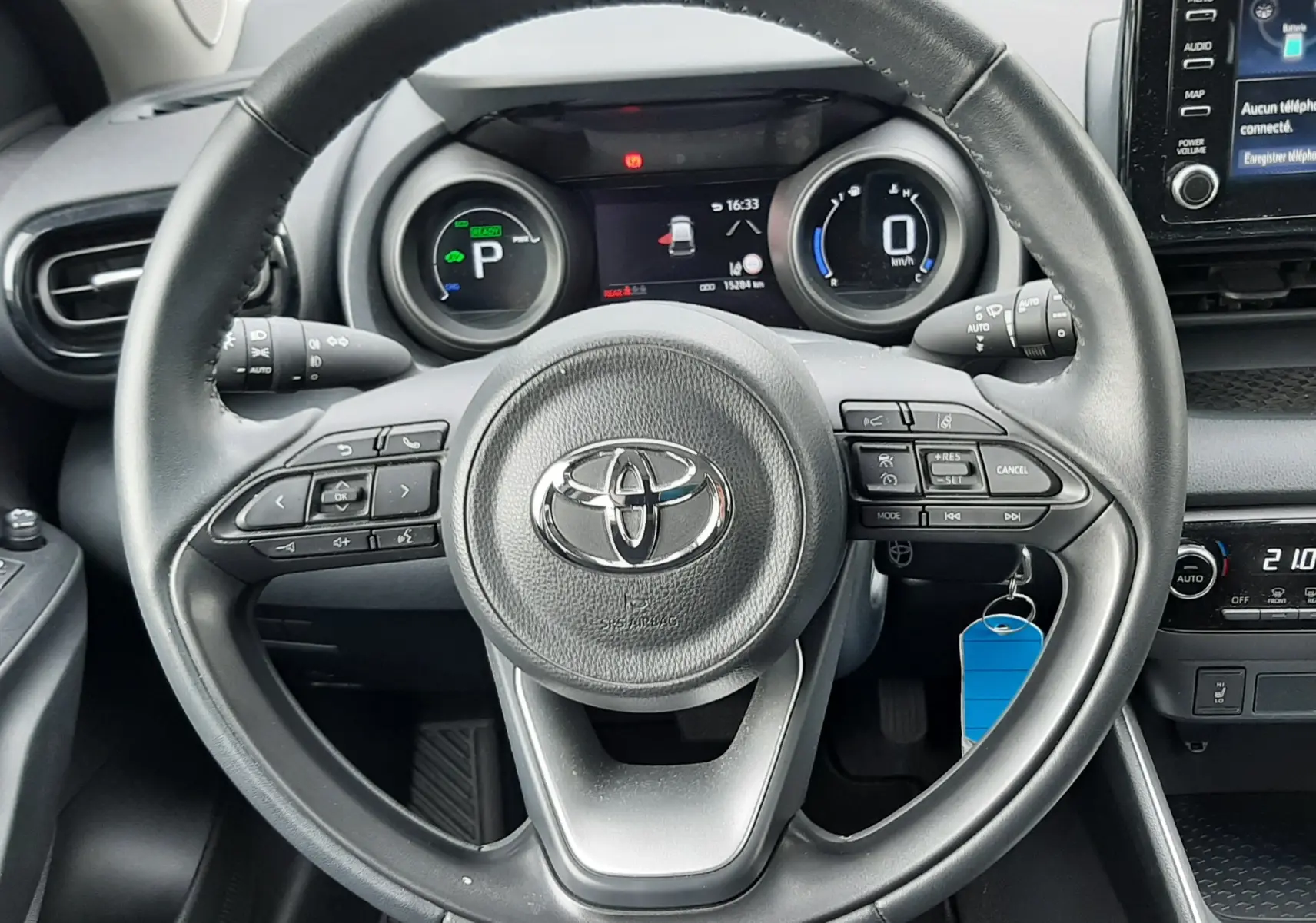 Vue intérieure centrée sur le volant noir de la Toyota Yaris 1.5 Hybrid 2023 avec tableau de bord digital et écran tactile.